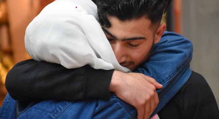 Um adolescente sírio se reencontrando com sua família em um aeroporto na Alemanha